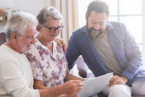 older couple and younger man looking at a laptop screen